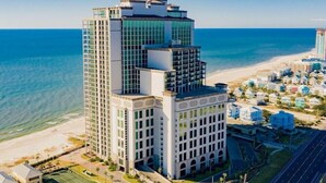 A high-rise hotel with multiple floors, located near a beach with clear blue waters. - The Oasis 2105 | Spacious, Lazy River, Poolside Grill, New Splash Pad, Pool with Slide! (Orange Beach)