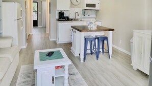 A compact living space with a kitchenette, a ceiling fan, a dining area with stools, and a small seating area with a coffee table. - Comfortable and affordable condo in four seasons. Monthly Discount Available. (Village of Four Seasons)