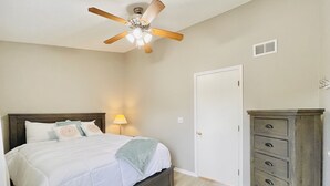 A bedroom with a bed, a ceiling fan, a dresser, and a door. - Comfortable and affordable condo in four seasons. Monthly Discount Available. (Village of Four Seasons)