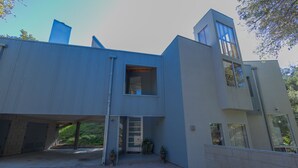 A modern two-story building with a flat roof, large windows, and a brick pathway leading to the entrance.