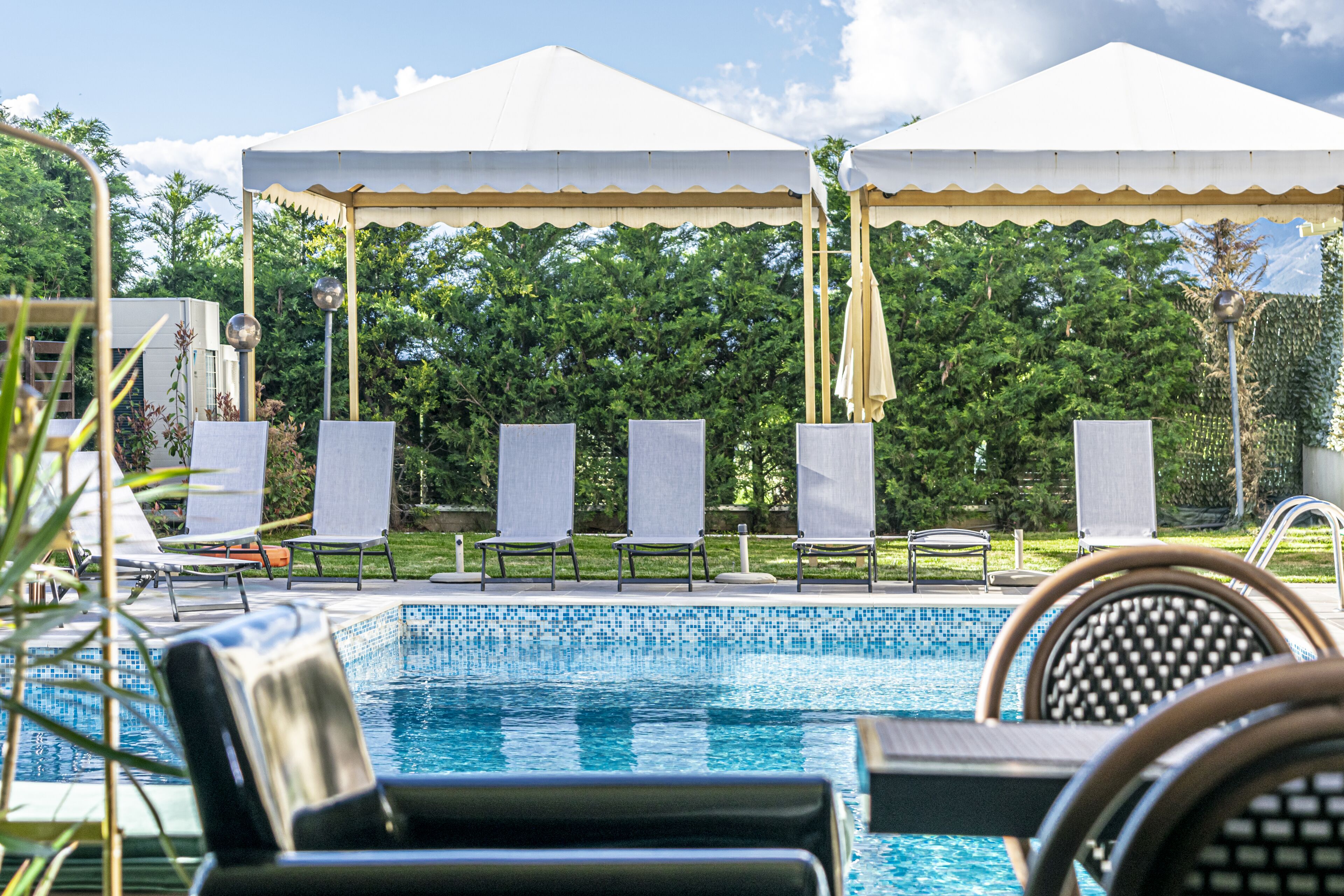 A pool area with lounge chairs and umbrellas under a canopy.