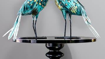 Deux oiseaux aux couleurs vives étaient perchés sur une table noire dont le pied était en forme de spirale.