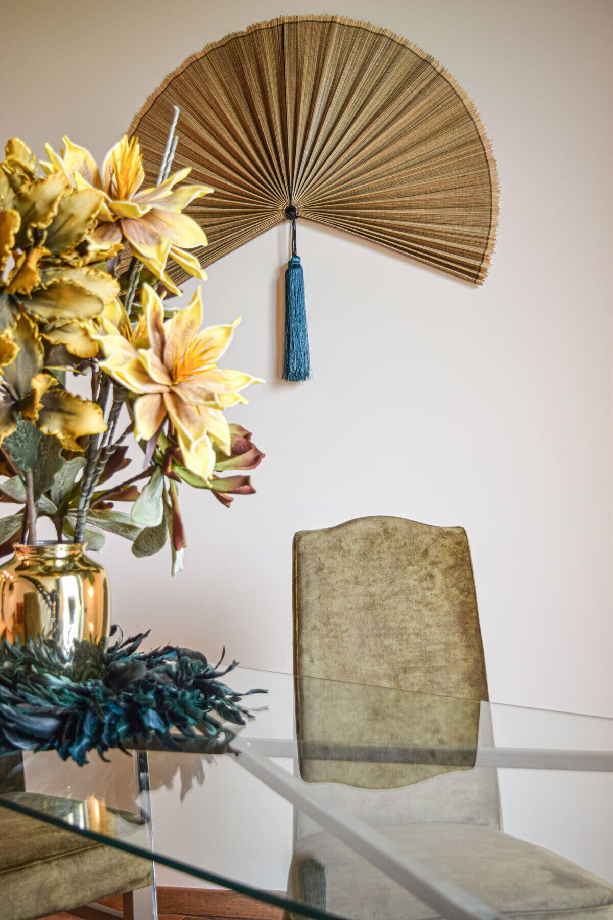 A dining table with a vase of flowers, a fan, and a chair.