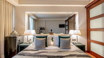 A hotel room with a large bed, two bedside tables, a mirror, and a television.