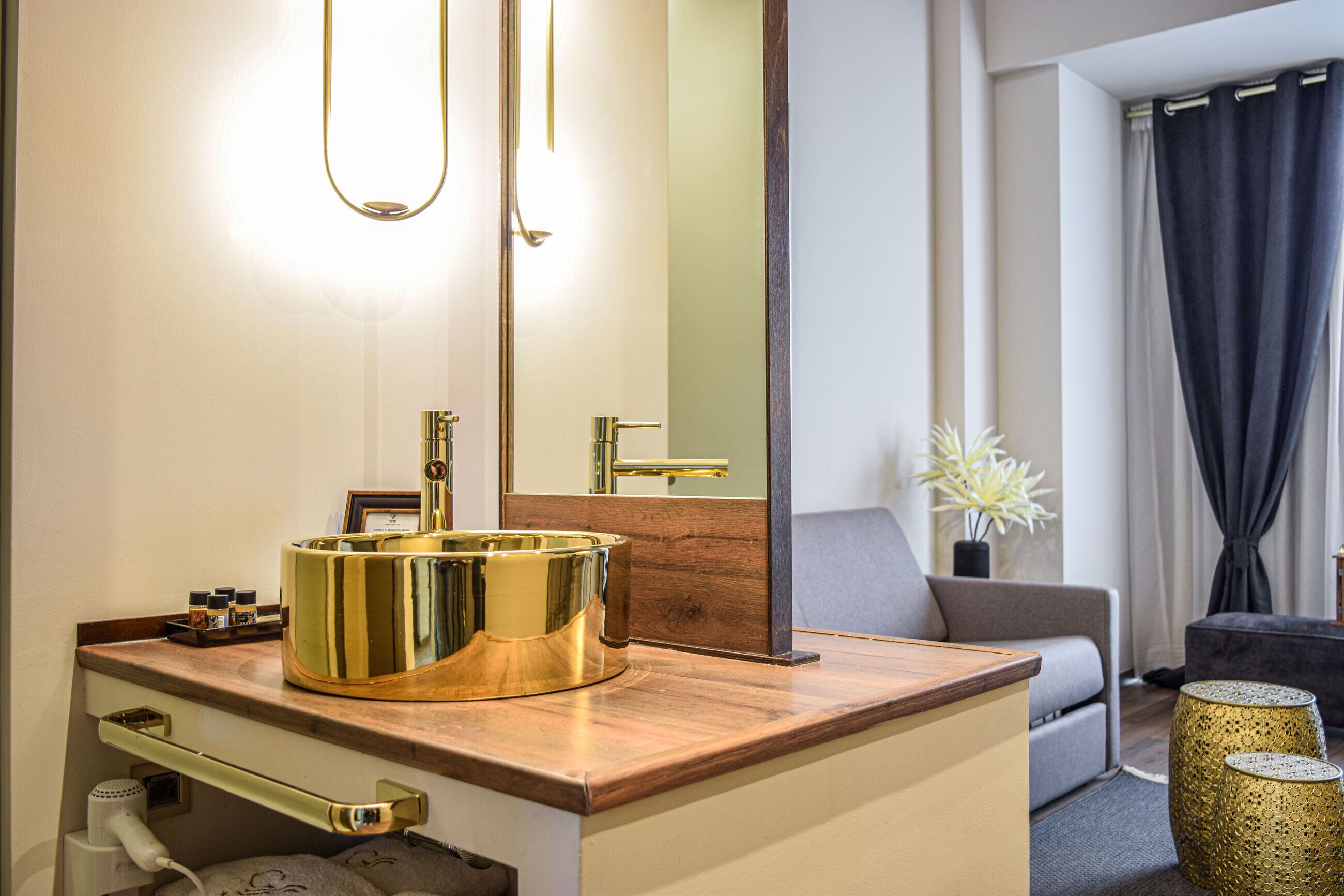 A modern bathroom with a gold vanity, a large mirror, and a wooden countertop.
