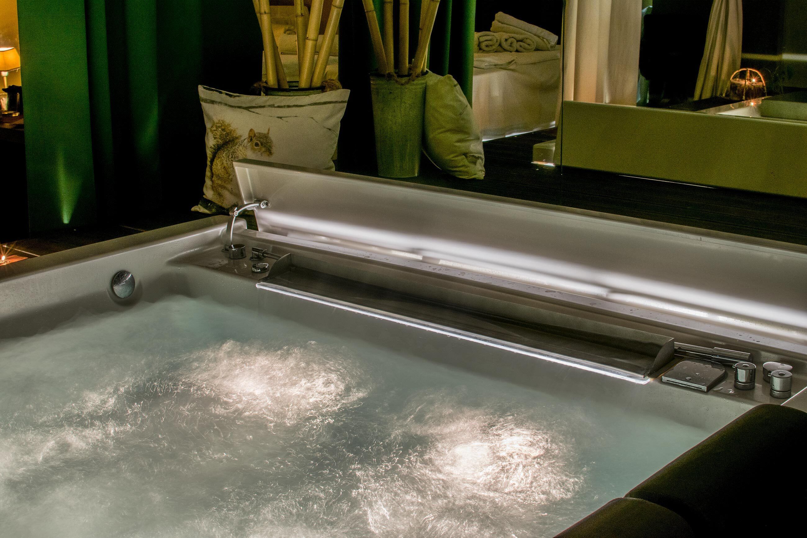 A bathtub with a faucet and control knobs, a towel rack, and a mirror reflecting the room.