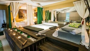 Um espaço de spa com uma banheira grande, mesa de massagem e um banco de madeira.