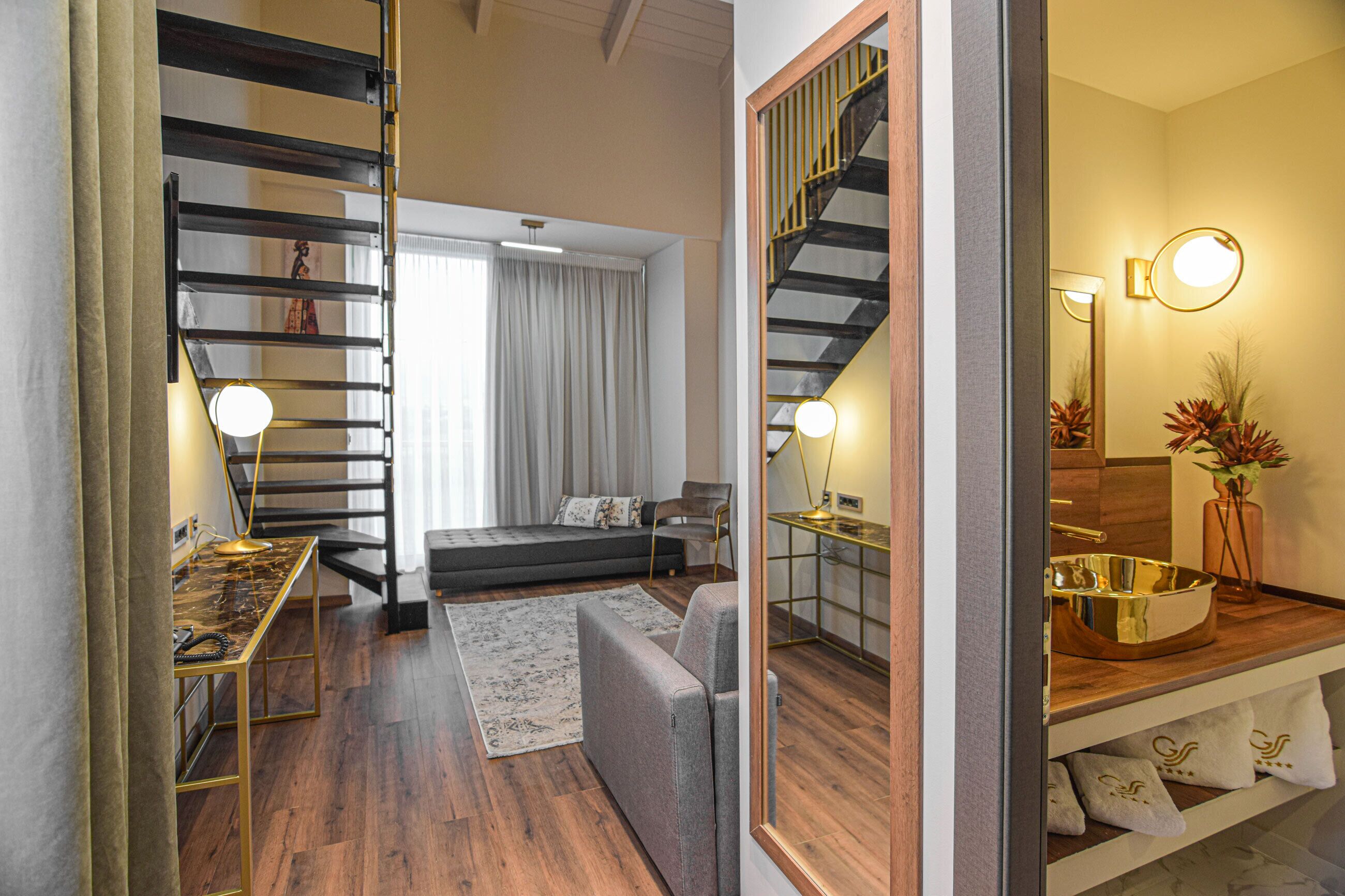 A modern living room with a sofa, a coffee table, and a staircase with a railing.