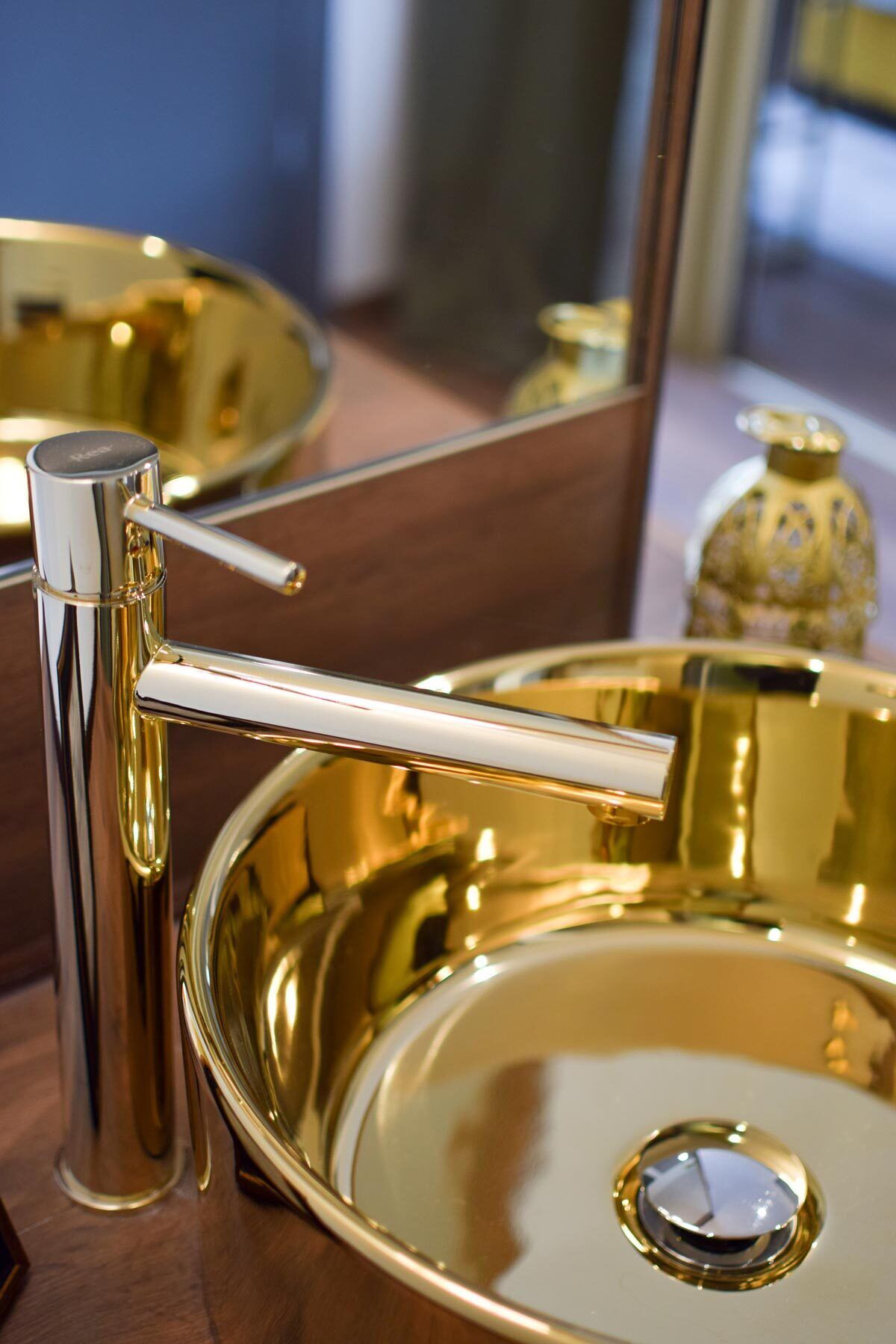 Un meuble-lavabo de salle de bain avec un lavabo doré, un robinet chromé et un miroir.