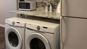 A compact kitchen with built-in appliances, including a microwave, a refrigerator, and a washing machine.