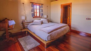 Un dormitorio con una cama de madera, una ventana con marco de piedra y una puerta de madera.