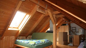 A small attic bedroom with a wooden bed, a skylight, and a wooden wardrobe. - Climbing hut Saxon Switzerland ... Wander ... Climb ... Relax (Gossdorf)