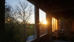 A room with a large window overlooking a forested area. - Climbing hut Saxon Switzerland ... Wander ... Climb ... Relax (Gossdorf)