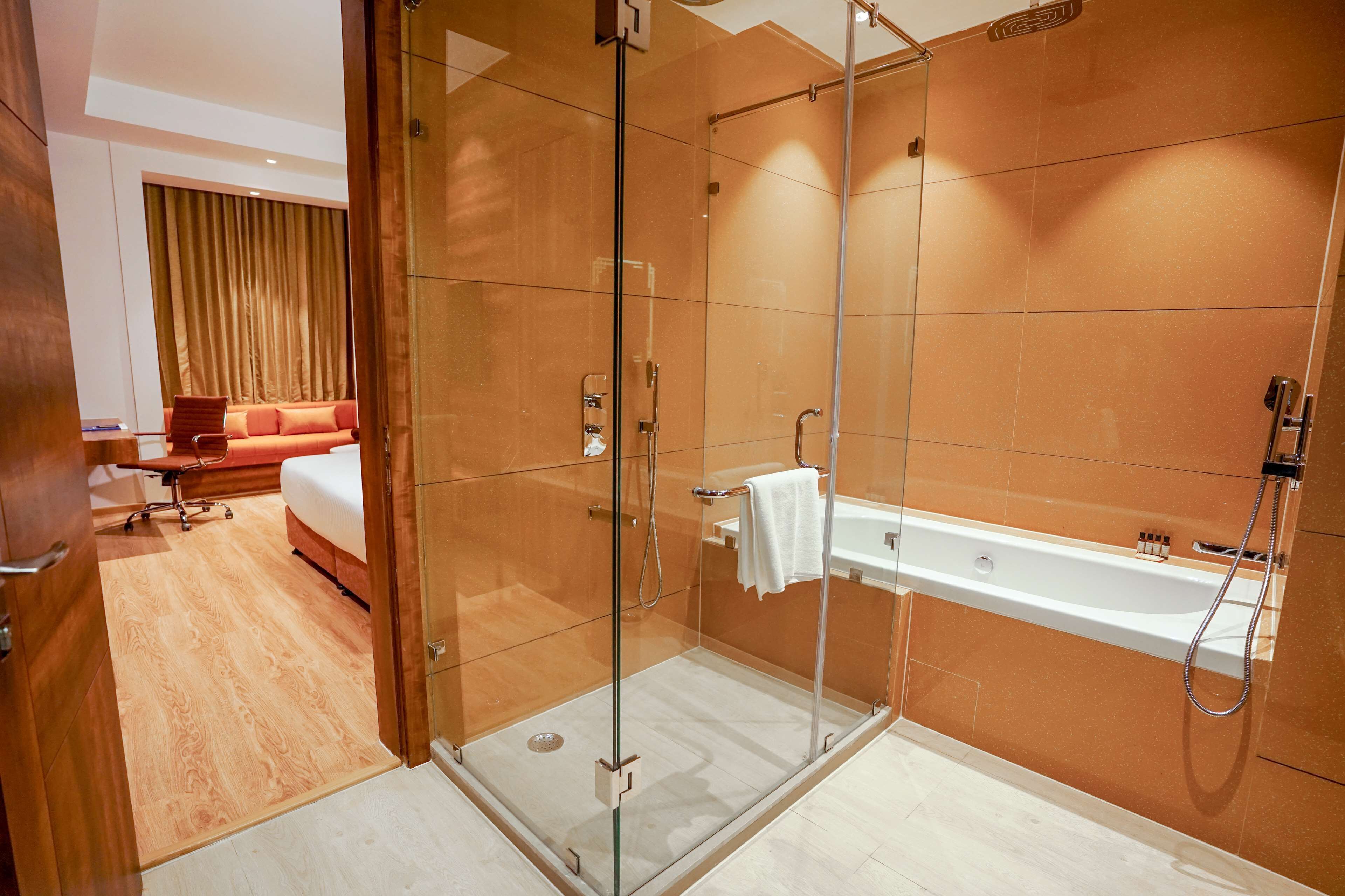 Une salle de bain moderne avec une douche à parois de verre, une baignoire blanche et un plancher en bois.