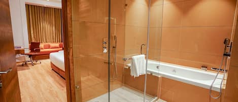 A modern bathroom with a glass-enclosed shower, a white bathtub, and a wooden floor.