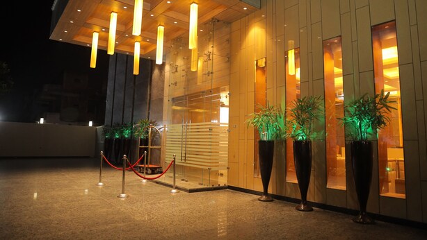 A modern building entrance with a reception desk, glass doors, and potted plants.