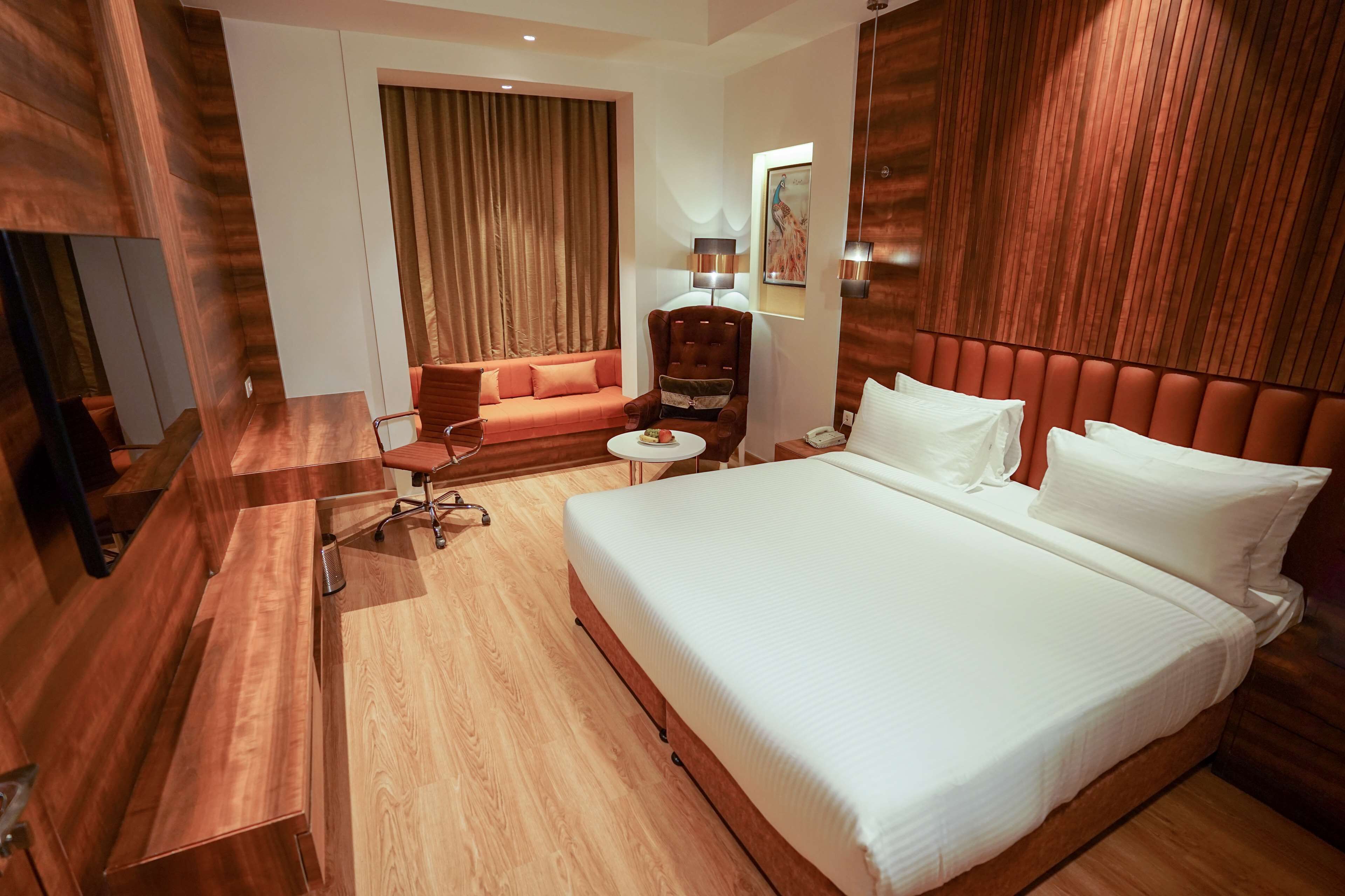 Een hotelkamer met een groot bed, een bank, een bureau en een stoel.