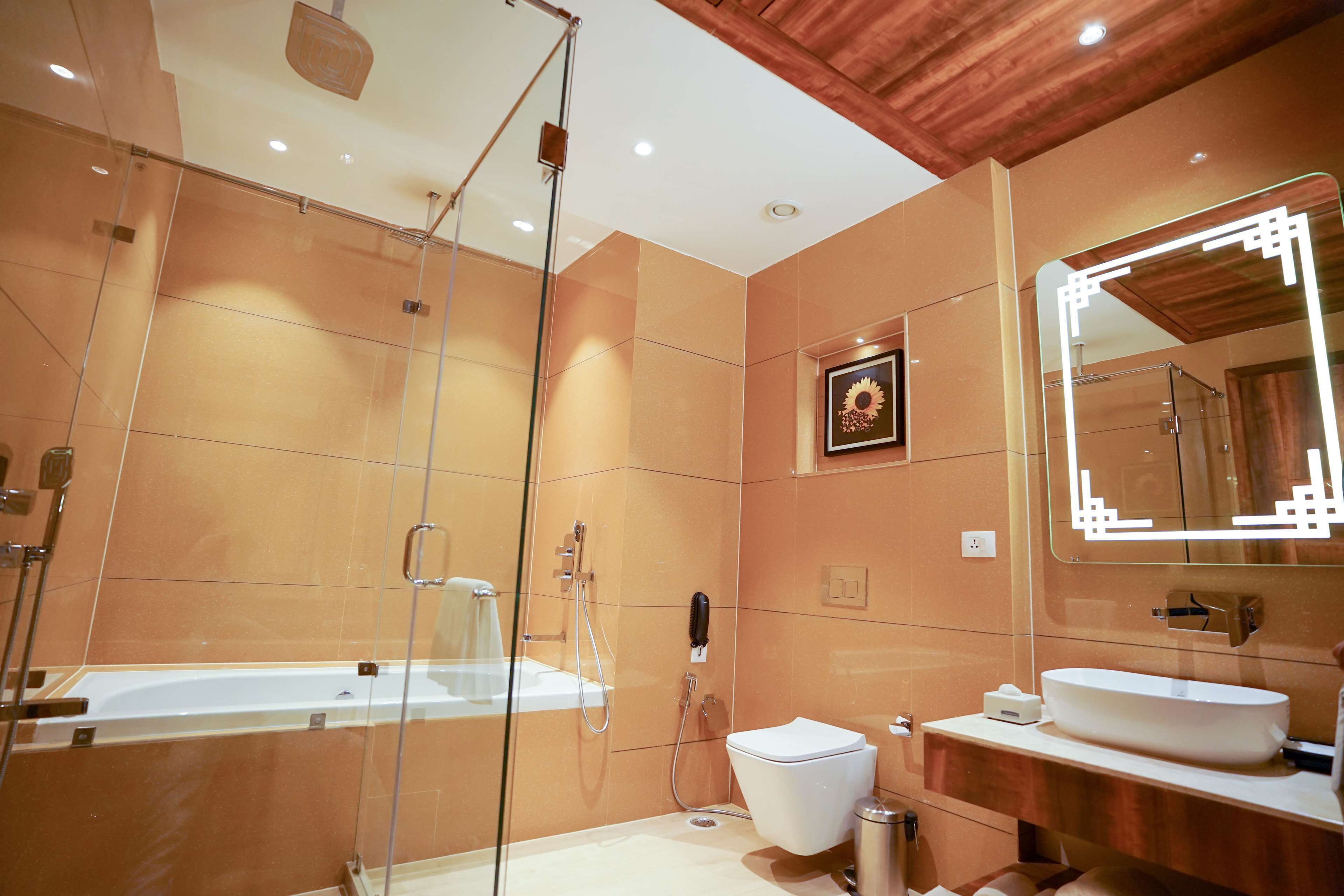 Ein modernes Badezimmer mit einer gläsernen Duschkabine, einer weißen Badewanne, einer Toilette und einem Waschtisch mit großem Spiegel.
