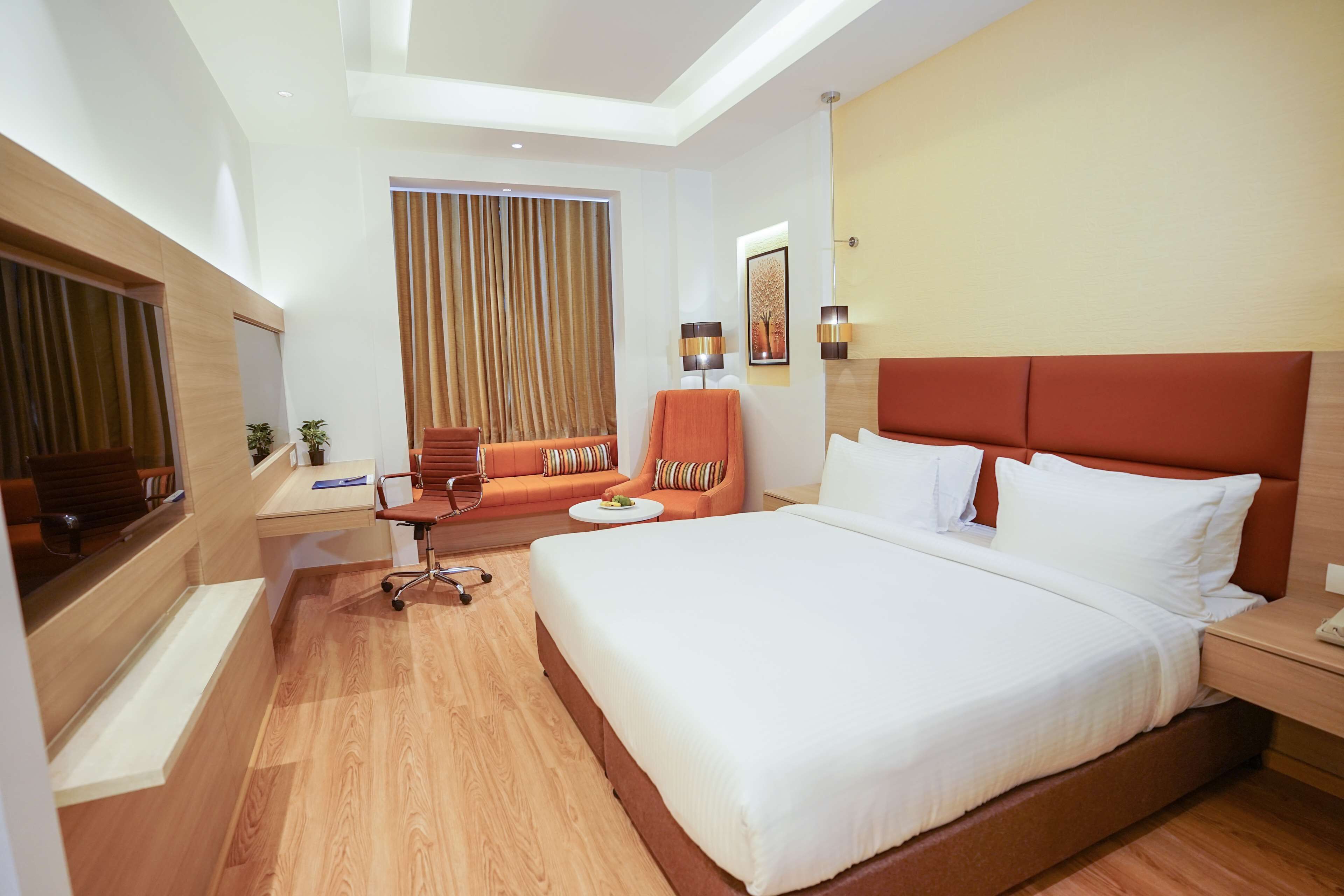 A hotel room with a large bed, a desk, a chair, and a TV.