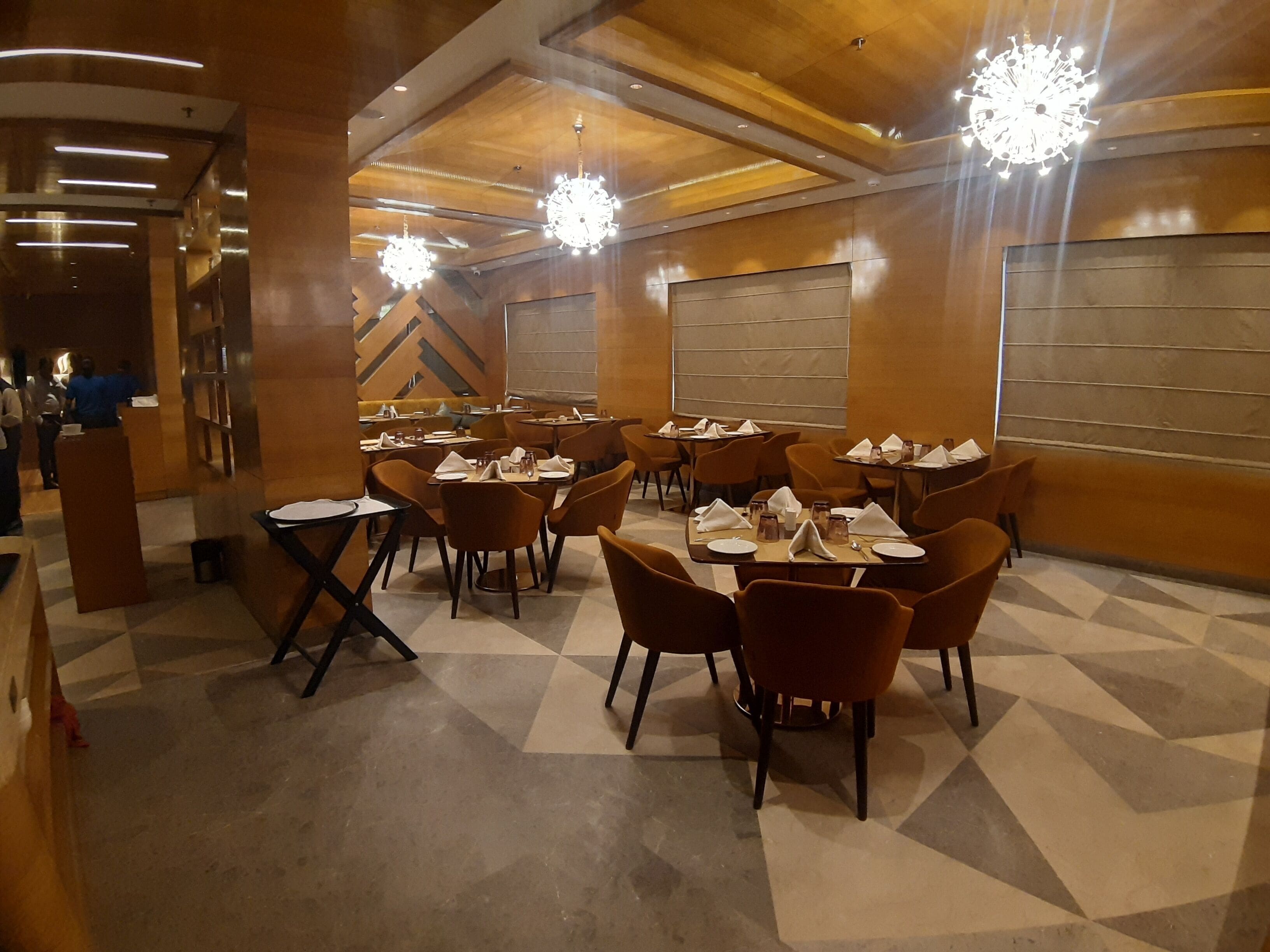 A restaurant with tables set for dining, a bar area, and a reception desk.
