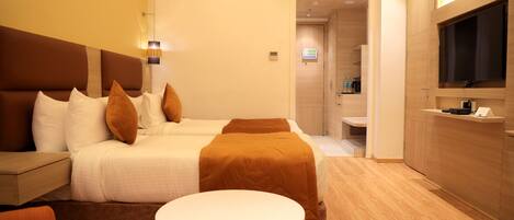 Ein Hotelzimmer mit Bett, einem kleinen Tisch, einer Couch, einem Fernseher und einem durch eine offene Tür einsehbaren Badezimmer.
