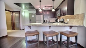 A modern kitchen with dark wood cabinets, a granite countertop, and three bar stools.