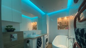 Un bagno moderno con lavandino, specchio, lavatrice e vasca da bagno.
