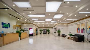 A spacious lobby with a reception desk, seating area, and artwork on the walls.