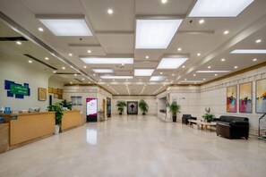 A spacious lobby with a reception desk, seating area, and artwork on the walls. - Tenglong Hotel (Kaili)
