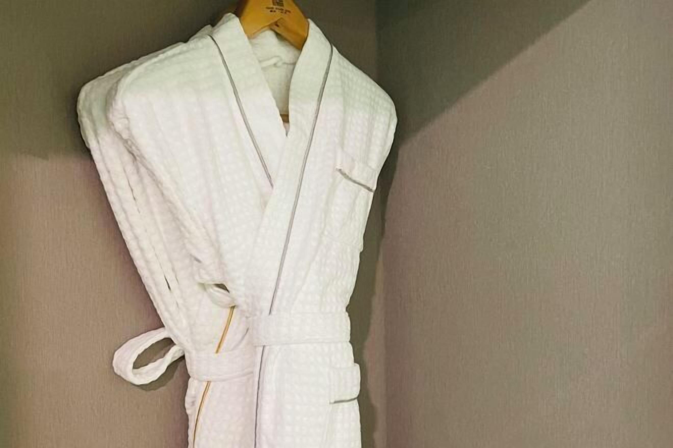 A white robe hanging on a wooden hanger.