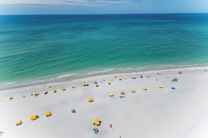 Une plage de sable blanc bordée d’une eau turquoise et cristalline.