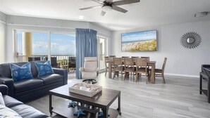 A living room with a sofa, coffee table, and a dining area with chairs and a table.