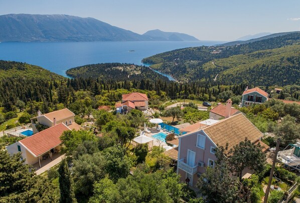 A residential area with houses, a swimming pool, and a view of a lake and mountains.