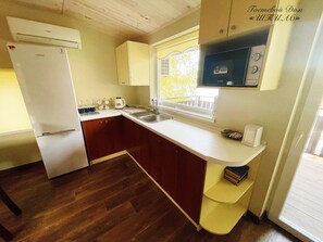 Een koelkast, een kookplaat, een waterkoker, kookgerei, borden en bestek