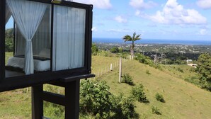 Une chambre à coucher avec un lit, des rideaux et une vue sur un paysage côtier.