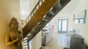 Un interior moderno con una escalera, una estatua de Buda, un sofá y una silla.