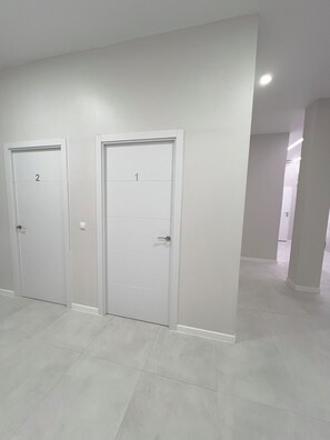 Un pasillo con dos puertas blancas, cada una con un número, que dan a habitaciones individuales.