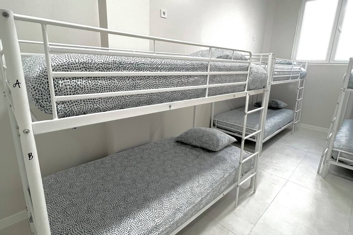 A bunk bed room with a window and white walls.