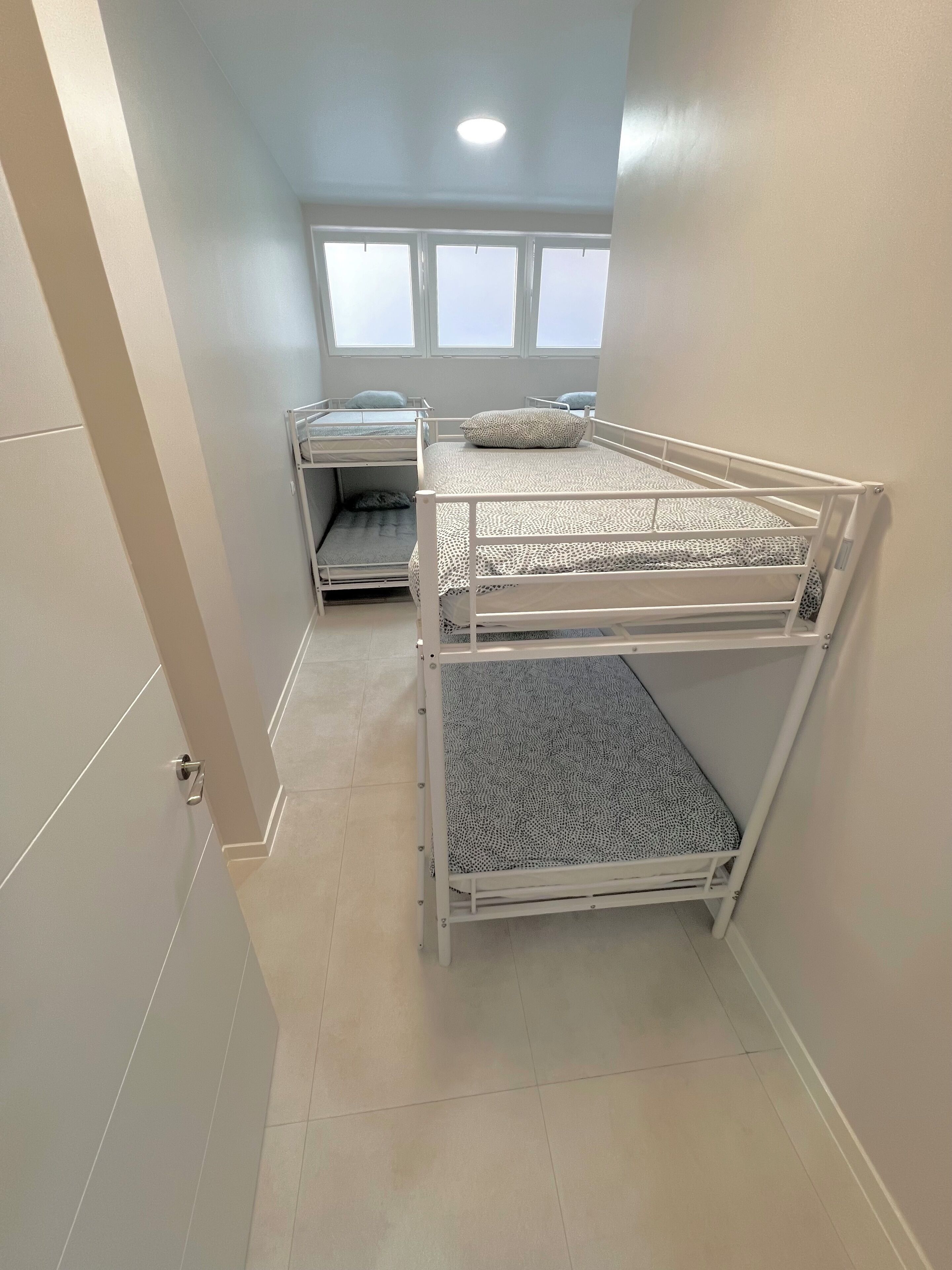 A room with bunk beds, a window, and a door.
