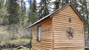 A small wooden cabin with a sloped roof, a window, and a star decoration on the side. - Whitetail Creek Camping Resort (Lead)