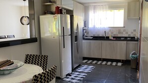 Een moderne keuken met een koelkast, fornuis en een eethoek.
