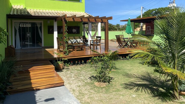 Een tweelaags huis met een groene gevel, een houten terras en een overdekte patio.