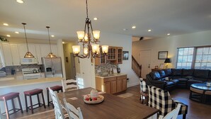A spacious kitchen with a dining area, wooden flooring, and a chandelier.