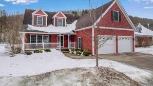 A red two-story house with a white porch and garage.