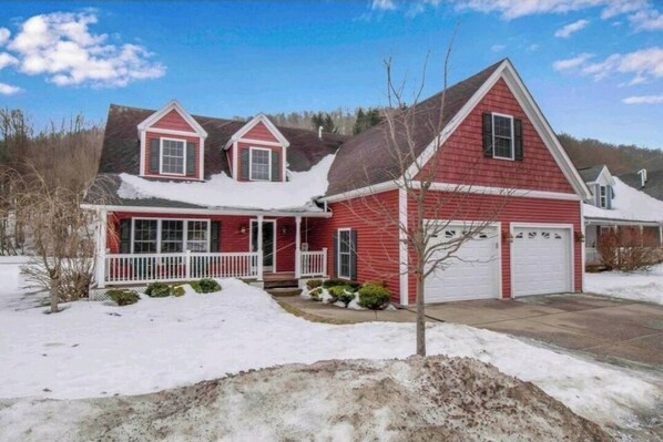 A red two-story house with a white porch and garage.