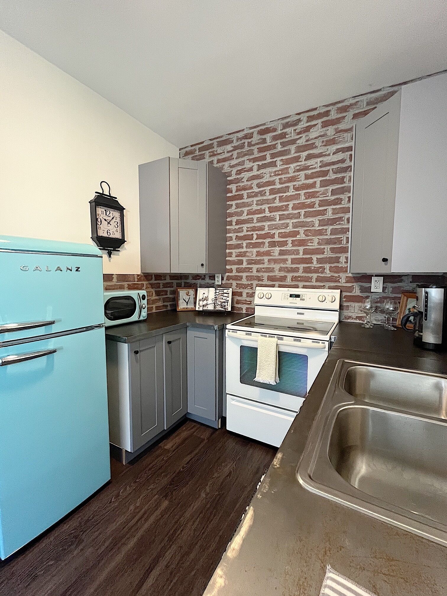 A kitchen with a blue refrigerator, a stove, and a sink.