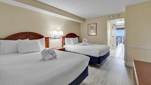 Habitación de hotel con dos camas, cabecero de madera, mesita de noche con lámparas y un cuadro en la pared.