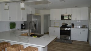 A modern kitchen with white cabinets, stainless steel appliances, and a marble island with stools. - Lakeview and direct access Boat Dock Lake Lewisville - Frisco/Little Elm
 (Frisco)