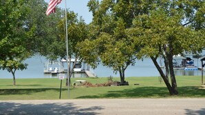 A flagpole with an American flag, a grassy area with trees, and a body of water in the background. - Lakeview and direct access Boat Dock Lake Lewisville - Frisco/Little Elm
 (Frisco)