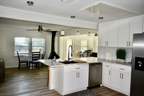 Een moderne keuken met witte kasten, een roestvrijstalen koelkast en een centraal eiland met een spoelbak.
